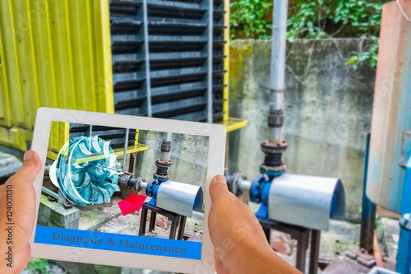 Fototapeta Industry 4.0 and Augmented reality for industry concept. Hand holding tablet with A/R maintenance application on screen to identify machine part repair with refrigeration container.