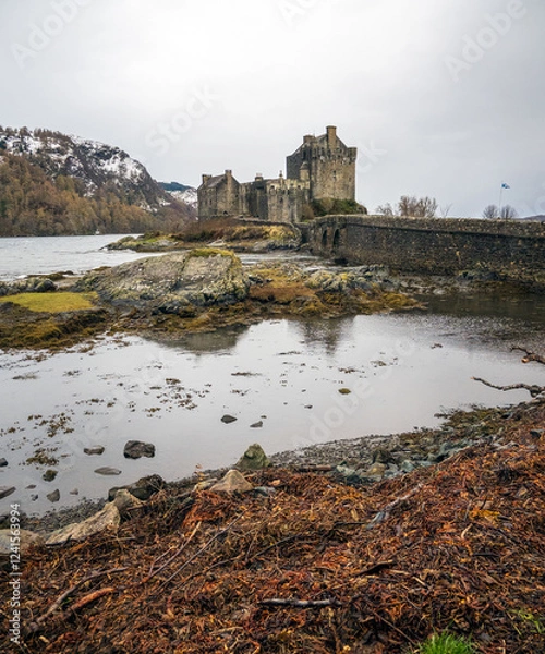 Fototapeta Eilean Donan Castle with bridge under a grey clouded sky in Scotland