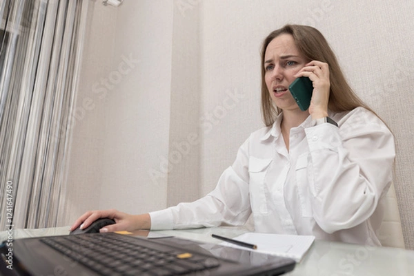 Fototapeta Female person office worker or freelancer concentrated works in office or at home at computer, talking on mobile phone. Business woman, successful entrepreneur solving important issues while working. 