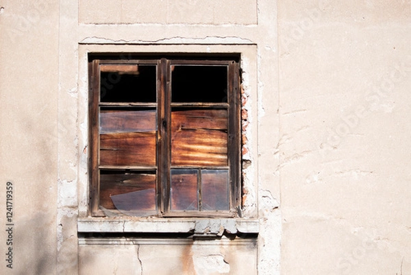Fototapeta Old wooden window with broken glass on the wall of an abandoned house