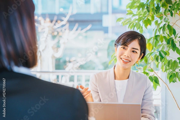 Obraz 明るい窓際で対面する人物に質問をする30代の転職のアドバイザーの女性