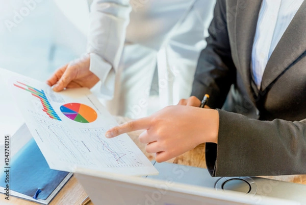 Obraz グラフや数値が分かるビジネスの資料を指さして情報を整理し分析しアドバイスする2人の女性の手元