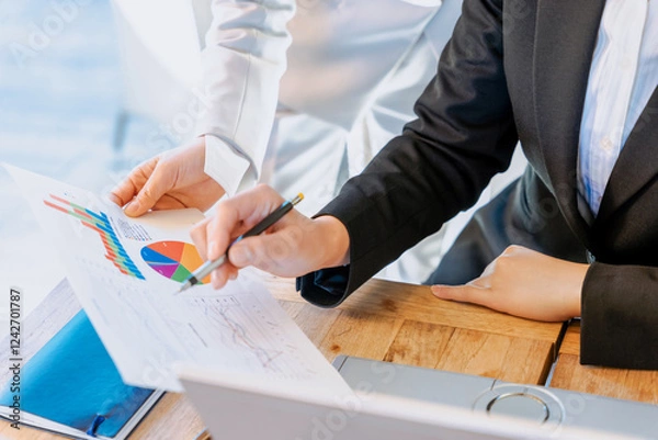 Obraz 数値やグラフといったデータをチームワークで分析する2人の女性の手元