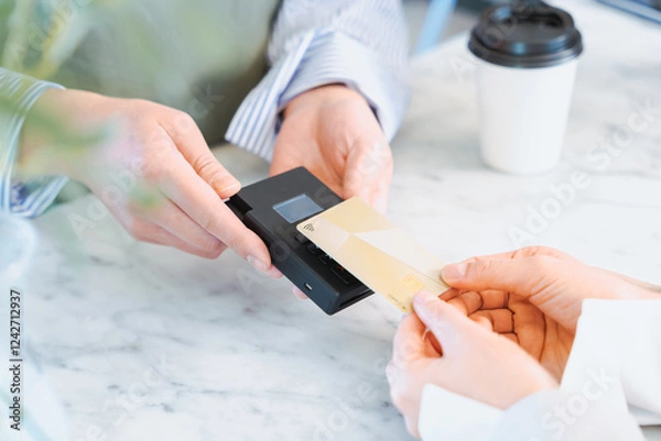 Obraz お店でコーヒーをクレジットカードのタッチ決済で購入する女性の手元