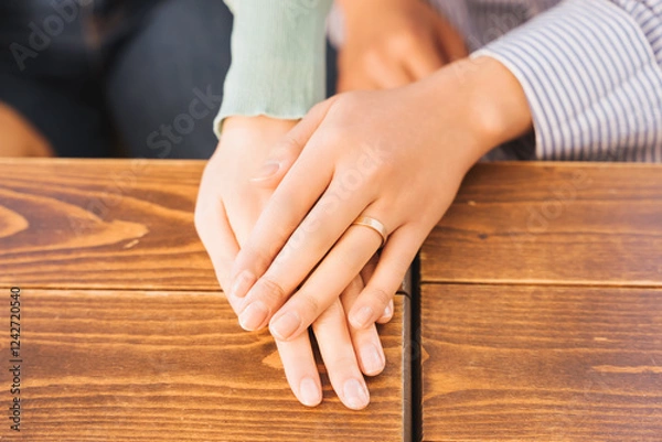 Obraz 机の上で手を重ね合う女性同士のカップルの指輪をはめた手元