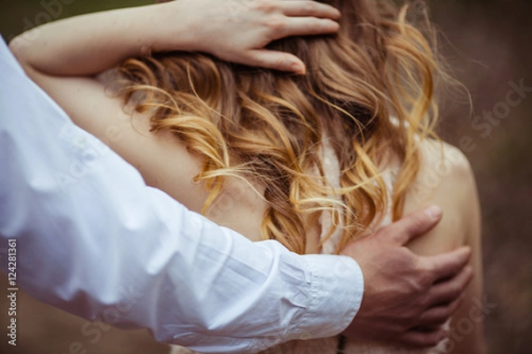 Fototapeta Man's broad palm touches woman's back covered with blonde curls