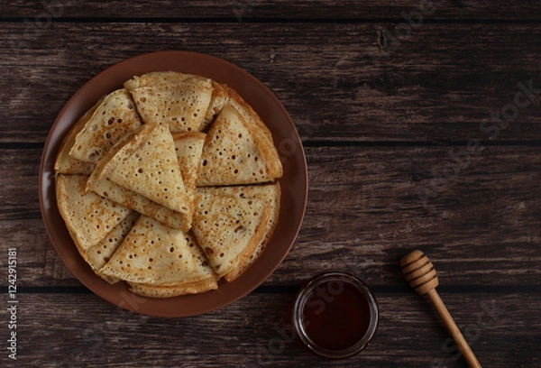 Fototapeta Baking openwork pancakes in a hole triangles on a plate on a dark background with honey