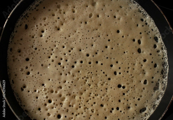 Fototapeta An openwork pancake is baked in a pan in a hole
