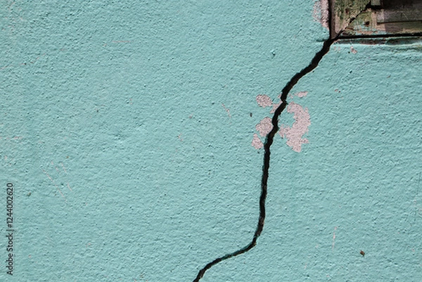 Fototapeta There is a large crack in the cement wall near the window frame of a house.