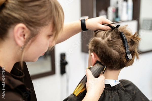 Fototapeta Child receiving a haircut in a modern salon during daytime with a focused stylist