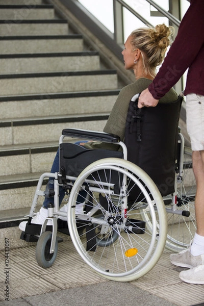 Fototapeta woman in a wheelchair in front of stairs