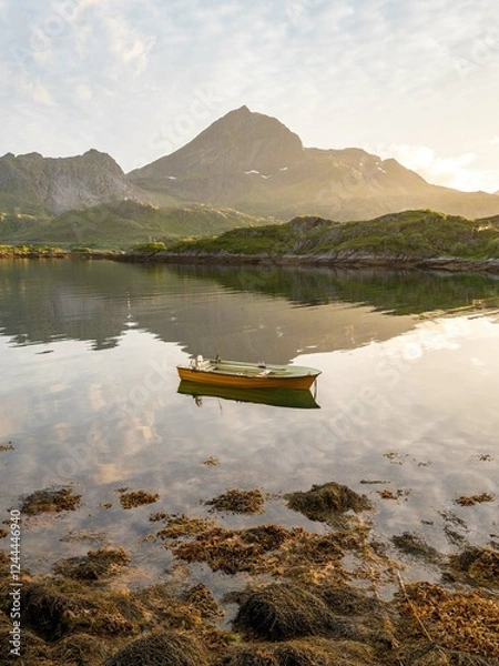 Obraz A boat at sunset on a tranquil fjord surrounded by mountains. 