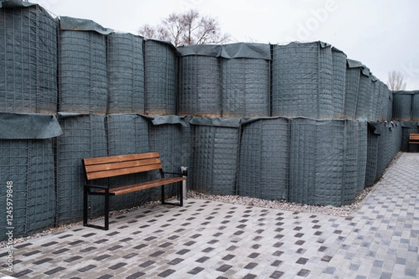 Fototapeta Rest area, smoking area on the street with protection from shrapnel, bullets and shells. Outdoor modular shelter, open-air shelters and bales of earth. Protection of equipment and buildings from shell