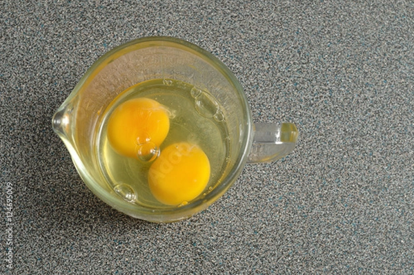 Obraz Two raw eggs in a measuring cup on a Grey worktop