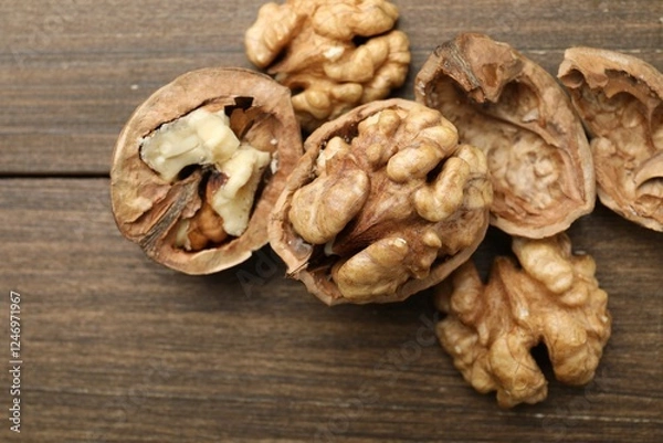 Fototapeta Fresh walnuts with shells on wooden table, flat lay