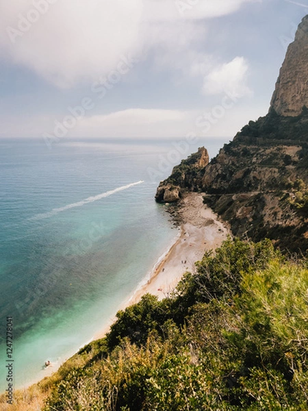 Fototapeta Motorboat sailing in sea near beach with its characteristic rock formations and crystalline waters popular tourist destination beach scene showcasing rocky cliffs and clear waters. vertical, film look