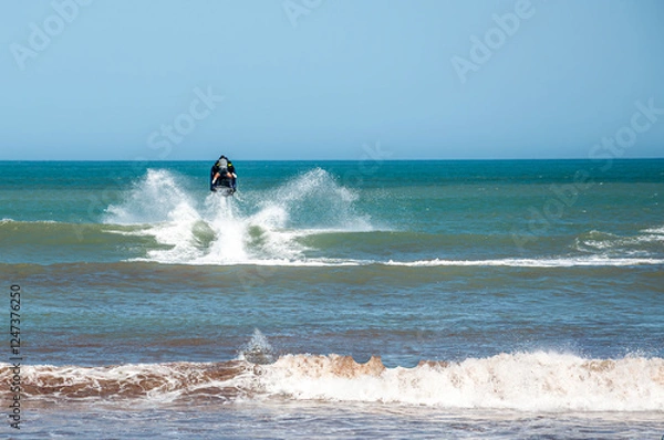 Fototapeta A jet ski jumping over the waves of the sea on a sunny day