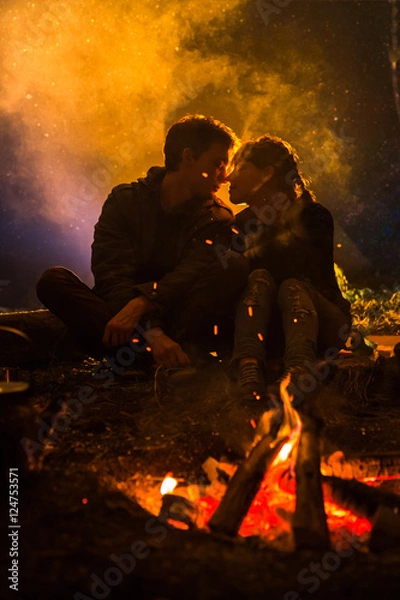 Fototapeta man plays guitar and woman about the fire on the background of the starry sky