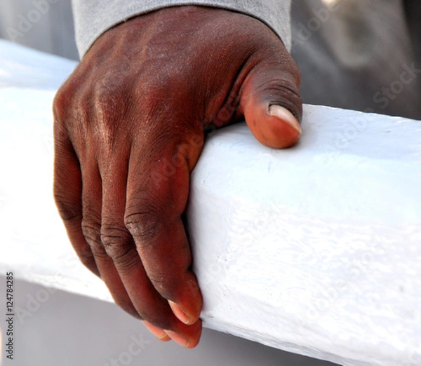 Fototapeta Dunkle Männerhand auf einem weißen Balken 