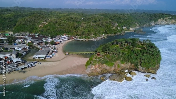 Fototapeta Aerial Drone view of the beach with white sand, coral rocks, hills with trees, waves from the ocean which is a tourist destination known as Drini Beach Gunung Kidul Yogyakarta