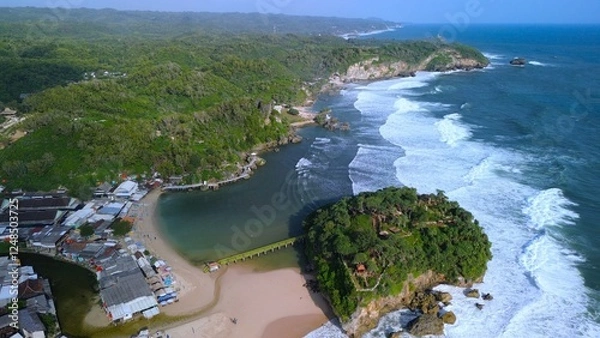 Fototapeta Aerial Drone view of the beach with white sand, coral rocks, hills with trees, waves from the ocean which is a tourist destination known as Drini Beach Gunung Kidul Yogyakarta