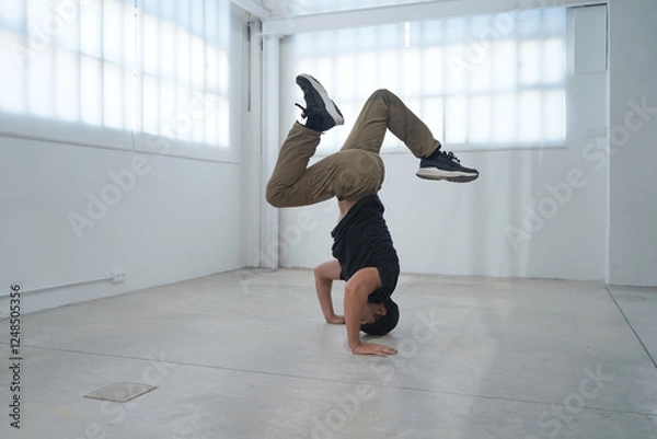 Fototapeta In a bright and spacious studio, a highly skilled breakdancer showcases their impressive dance talent. High quality photo