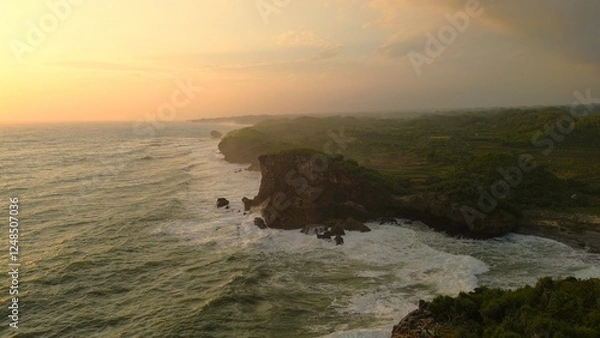 Fototapeta Bird eye view Sunset on the edge of the ocean bordering coral hills with waves from the sea at Krakal Beach, Gunung Kidul, Yogyakarta