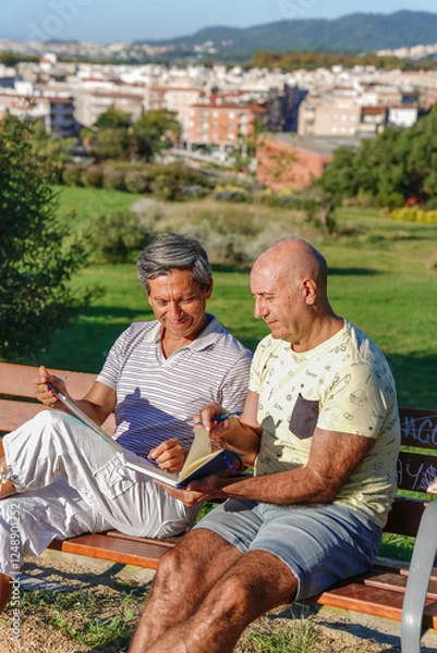Fototapeta Two mature men smiling while using a tablet together