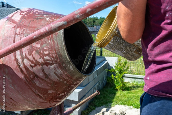 Obraz Mixing different ingredients for concrete in a portable concrete mixer.
