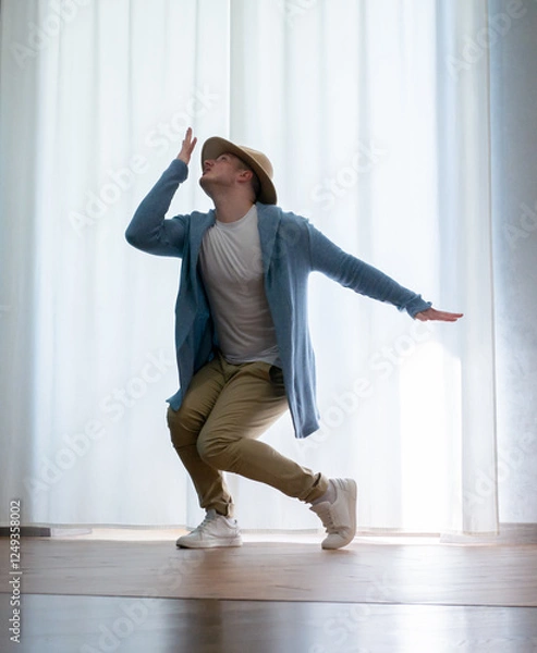 Fototapeta Young guy dancer in motion in a pose. A man performs a modern dance in casual clothes.
