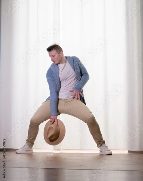 Obraz Young guy dancer in motion in a pose. A man performs a modern dance in casual clothes.