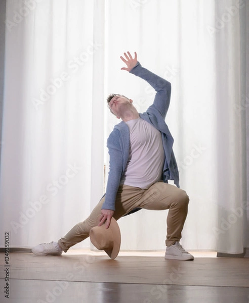 Obraz Young guy dancer in motion in a pose. A man performs a modern dance in casual clothes.