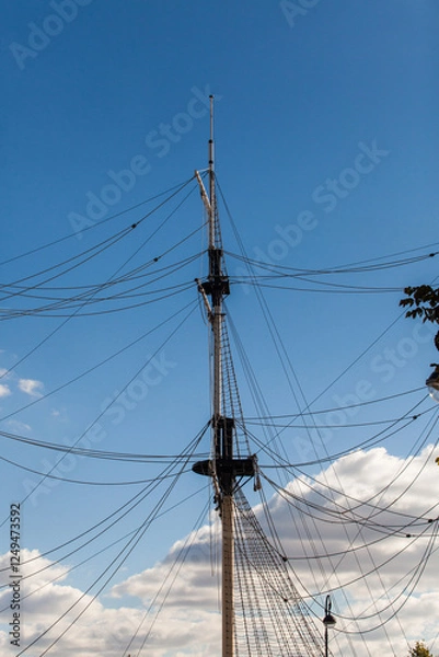 Obraz Masts of an old sailing ship against a blue sky. Old sailing boat rigging