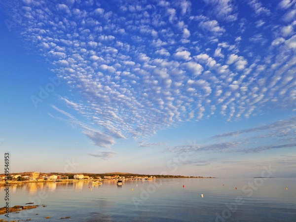 Obraz Scenic coastal town with rippled cloud formations over calm sea at sunset