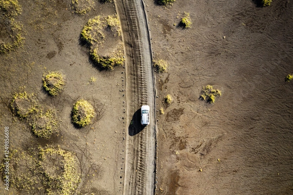 Obraz A drone shot showing a white vehicle traveling along a narrow dirt road a desert landscape near Landmannalaugar called Rainbow Mountains in Iceland. Emphasizing isolation, travel, and exploration