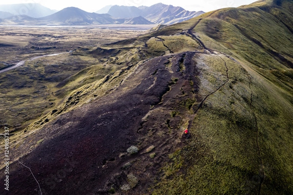 Obraz Stunning aerial image showcasing a woman walking over volcanic crater surrounded Landmannalaugar mountains and by hills and expansive wilderness, emphasizing the raw beauty and geology of volcanic