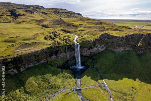 Obraz A magnificent aerial view Seljalandsfoss waterfall in Iceland plunges over the edge of green cliffs, surrounded by stunning countryside. The serene landscape captures beauty of untouched nature
