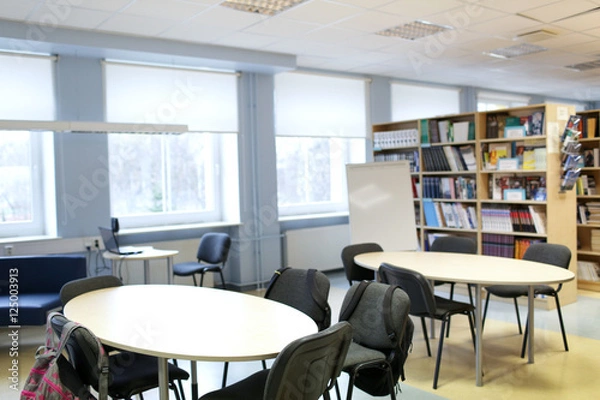 Fototapeta tables with chairs and backpacks at library room