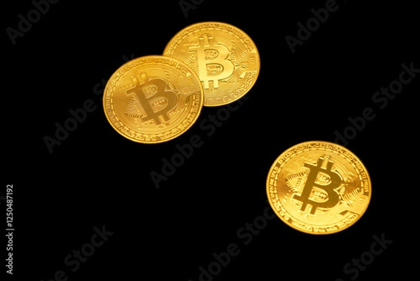Fototapeta Three golden Bitcoin coins on a black background, symbolizing cryptocurrency and representing the digital financial world. Isolated.