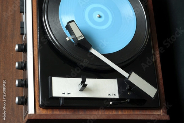 Obraz Retro stereo vinyl record player in brown wooden case playing blue flex record. Top view close up