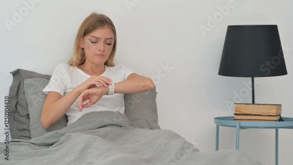 Fototapeta Young Woman Checking Time while Waiting in Bed