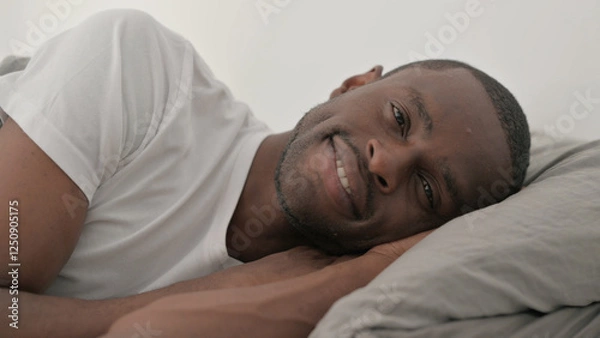 Obraz Close up of Smiling African Man Lying on Side in Bed