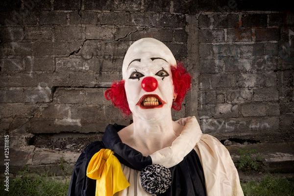 Obraz angry clown standing in front of a wall