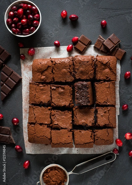 Fototapeta Chocolate brownies with cranberries on dark background. Overhead shot