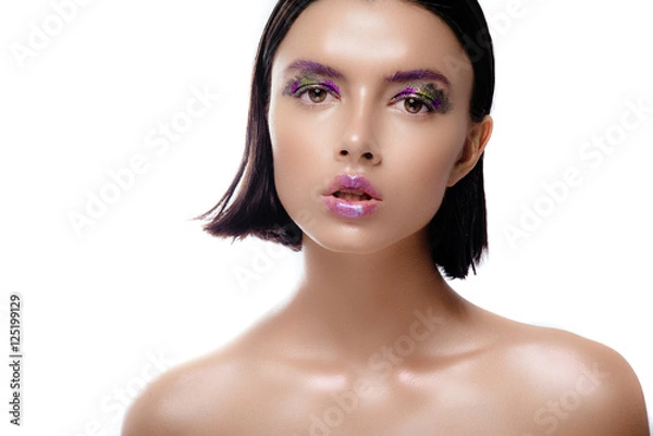 Fototapeta Beautiful woman model with shiny skin posing on a white background. The brunette with wet hair and a gentle colorful makeup.