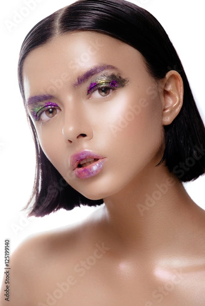 Fototapeta Beautiful woman model with shiny skin posing on a white background. The brunette with wet hair and a gentle colorful makeup.