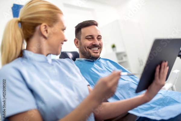 Fototapeta Smiling Patient At Dentist Reviewing X-rays On Tablet