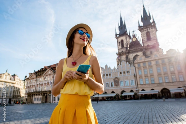 Obraz Młoda kobieta w żółtym spaceru z inteligentny telefon na rynku starego miasta w Pradze