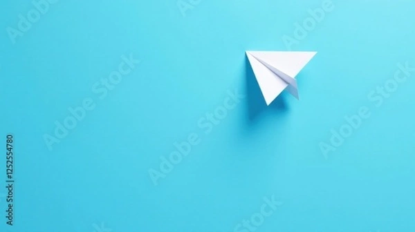 Fototapeta A solitary paper airplane gracefully glides across a vibrant azure backdrop, symbolizing dreams of flight and the boundless possibilities that await.