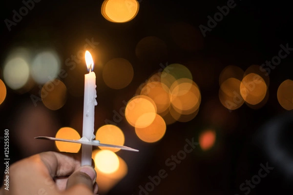 Obraz Blurred image for background of hand with candle memorable for King Bhumibol Adulyadej of thailand